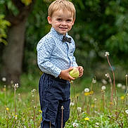 Raphaël a rejoint le concours — aidez-le/la à gagner de superbes lots ! child, boy, smile, apple, bow_tie, polka_dot_shirt, pants, grass, dandelions, outdoor, nature, field, greenery, portrait, happy, cute, standing, young, person, casual