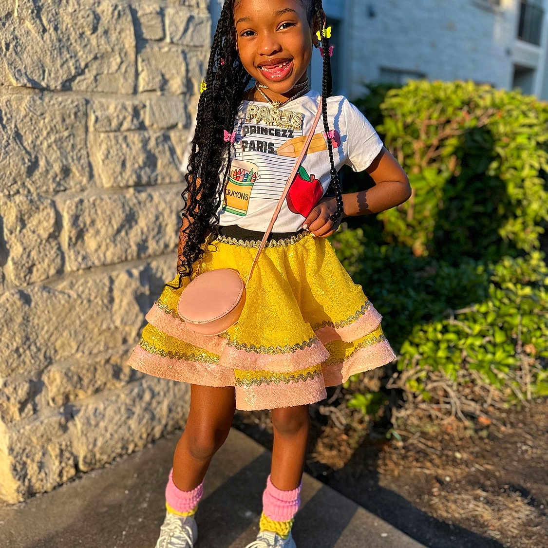 Pa'Ryss is registered to the contest to win money with this photo: blackhair, braid, child, clothing, curlyhair, face, female, footwear, girl, hair, happy, head, person, shoe, sitting, skirt, sleeve, smile, standing, student