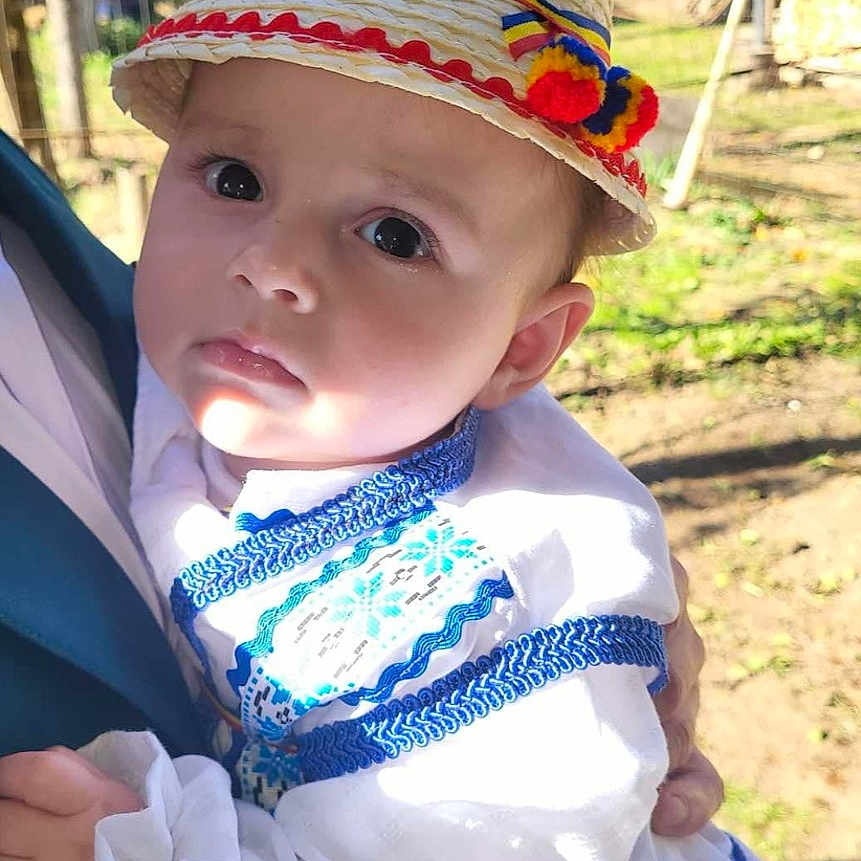 Darius is registered to the contest to win money with this photo: baby, cap, clothing, coat, costume, dress, face, grass, hat, head, land, nature, outdoors, person, photography, plant, portrait, sunhat, tree, vegetation