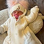 baby, infant, sleeping, knitted_clothing, white_outfit, hat, pom_poms, pacifier, pink, plush_cushion, cozy, cute, child, resting, indoor, soft_texture, warm, newborn, person, portrait