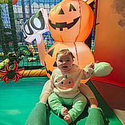 Emie joined the competition — help win amazing prizes! baby, child, infant, person, legs, jeans, ripped_jeans, pumpkin, halloween, inflatable, jack_o_lantern, toy, netting, spider, play_area, indoor, colorful, happy, smiling, cute