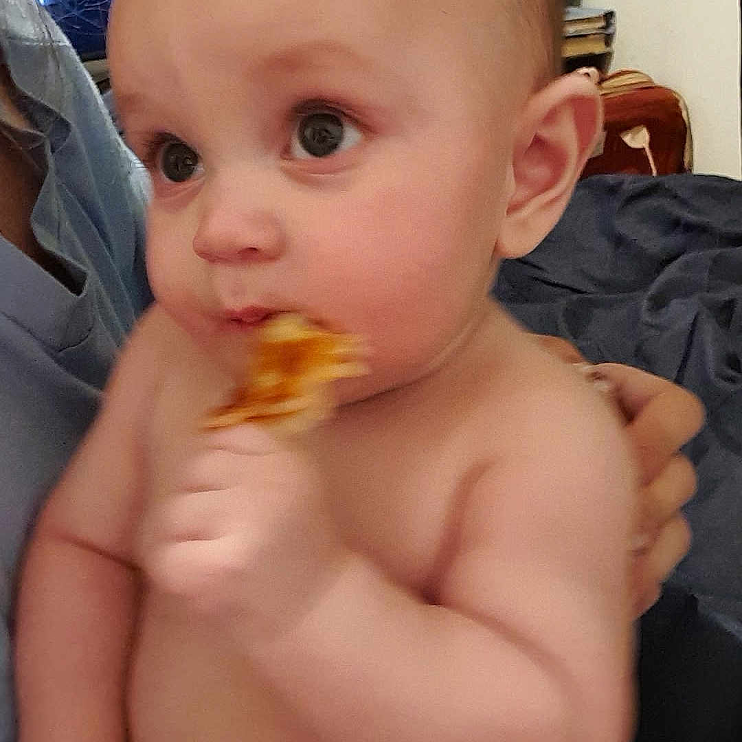 Jasper-Riley joined the competition — help win amazing prizes! adult_hand, baby, candid, child, closeup, curious, cute, diaper, eating, expression, face, furniture, hand, indoor, person, pizza, plush, shirtless, skin, television