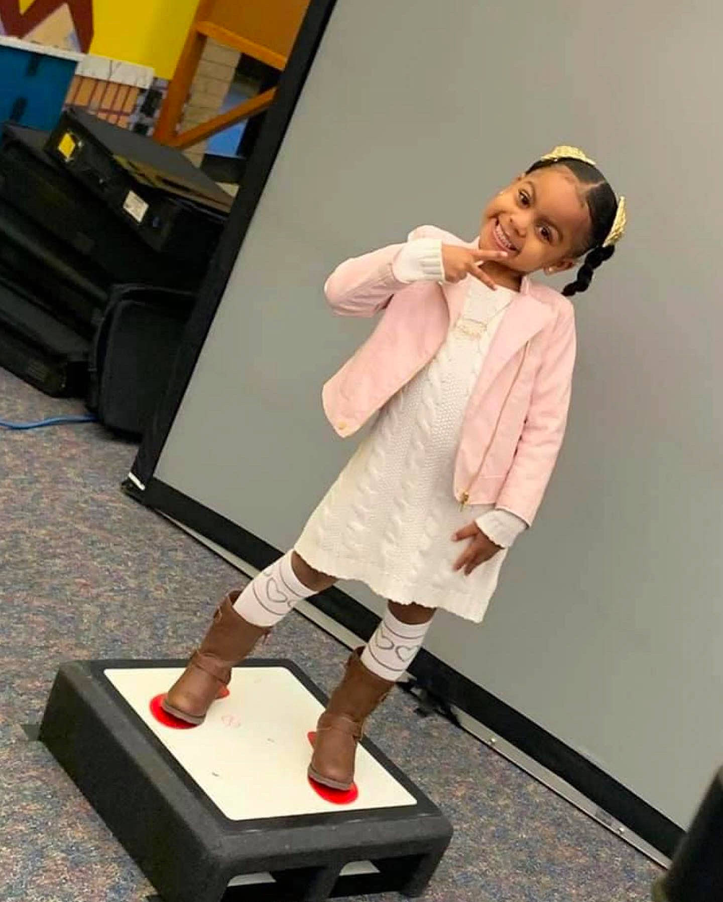 Alaya Scott is registered to the contest to win money with this photo: balance, boot, calf, event, face, fashion_design, flooring, fun, high_heels, human_leg, joint, joy, knee, leg, person, shoulder, sitting, sleeve, smile, sock