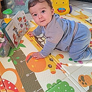 Sacha a rejoint le concours — aidez-le/la à gagner de superbes lots ! baby, child, clothing, colorful, crawling, curious, eyes, floor, giraffe, hands, head, indoor, person, plastic_container, play_mat, soft_lighting, storybook, toys, yellow_toy, young