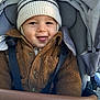 Sacha a rejoint le concours — aidez-le/la à gagner de superbes lots ! baby, child, smiling, tongue_out, hat, knit_hat, jacket, brown_jacket, stroller, seatbelt, happy, cute, warm_clothing, outdoor, person, infant, young_child, face, headwear, playful