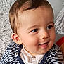baby, child, face, smile, curly_hair, striped_clothing, cardigan, button, cute, portrait, infant, happy, seated, indoor, soft_texture, furniture, person, closeup, expression, skin
