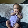 baby, child, infant, portrait, sitting, couch, cushion, blanket, purple_outfit, onesie, indoors, home, cozy, wide_eyed, hands, barefoot, smiling, natural_light, close_up, candid