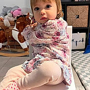 Malya participe au concours pour gagner de l'argent avec cette photo : toddler, child, sitting, chair, floral_clothing, pink_pants, polka_dot_socks, indoor, playroom, rocking_horse, stuffed_animals, carpet, curious_expression, young_child, small_chair, portrait, person, floor, home, cute