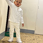 Sami a rejoint le concours — aidez-le/la à gagner de superbes lots ! toddler, child, white_clothing, cardigan, pants, sneakers, indoors, floor, mosaic, railing, hand, door, wall, curious, standing, person, young_child, portrait, footwear, casual