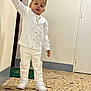 toddler, child, white_clothing, cardigan, pants, sneakers, indoors, floor, mosaic, railing, hand, door, wall, curious, standing, person, young_child, portrait, footwear, casual
