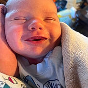 Waylon is registered to the contest to win money with this photo: baby, blanket, child, closeup, clothing, cozy, cute, face, happy, indoors, infant, newborn, portrait, relaxed, resting, sleeping, smiling, soft, toddler, warm