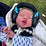 Waylon joined the competition — help win amazing prizes! baby, newborn, sleeping, headphones, ear_protection, blanket, pacifier, outdoor, grass, infant, clothing, hand, face, person, soft_texture, peaceful, wrapped, cute, child, protective_gear