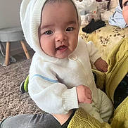 Adria participe au concours pour gagner de l'argent avec cette photo : baby, child, person, indoor, hoodie, white_clothing, yellow_sweater, carpet, holding, cute, smiling, face, hand, seated, cozy, furniture, plush, casual, portrait, young_child