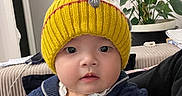 Adria participe au concours pour gagner de l'argent avec cette photo : baby, child, yellow_hat, pom_pom, knit_hat, blue_sweater, indoor, plant, face, curious, seated, portrait, clothing, cozy, cute, person, headwear, warm_clothes, home, infant