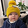 baby, blue_sweater, child, clothing, cozy, curious, cute, face, headwear, home, indoor, infant, knit_hat, person, plant, pom_pom, portrait, seated, warm_clothes, yellow_hat
