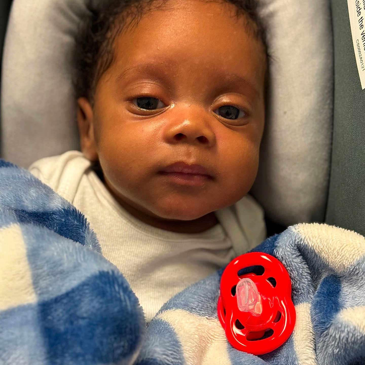 Aidyn joined the competition — help win amazing prizes! baby, infant, child, portrait, face, eyes, sleepy, seated, blanket, blue_blanket, white_clothing, pacifier, red_pacifier, padded_seat, cozy, indoor, close_up, photography, baby_carrier, calm