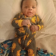 La'Treyveonn joined the competition — help win amazing prizes! baby, infant, child, onesie, lion_pattern, bed, blanket, pillow, smile, curly_hair, cute, sleepwear, indoor, lying_down, young_child, face, hand, fabric, cozy, soft_lighting