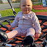 baby, child, swing, playground, outdoor, sunlight, net_swing, pink_clothing, shoes, grass, slide, fence, residential_area, daytime, person, happy, sitting, toy, fun, play