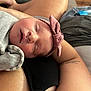 Ellie is registered to the contest to win money with this photo: newborn, baby, sleeping, blanket, headband, pink_bow, arm, tattoo, indoor, person, rest, cozy, closeup, soft_light, skin, clothing, bedroom, fabric, comfort, peaceful