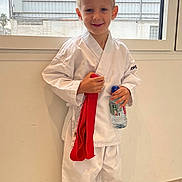 Palchykov Oleksandr a rejoint le concours — aidez-le/la à gagner de superbes lots ! child, boy, karate_gi, red_belt, water_bottle, barefoot, indoor, window, cloudy_sky, smiling, blond_hair, martial_arts, pose, floor_tiles, casual, young, portrait, standing, white_clothing, happy