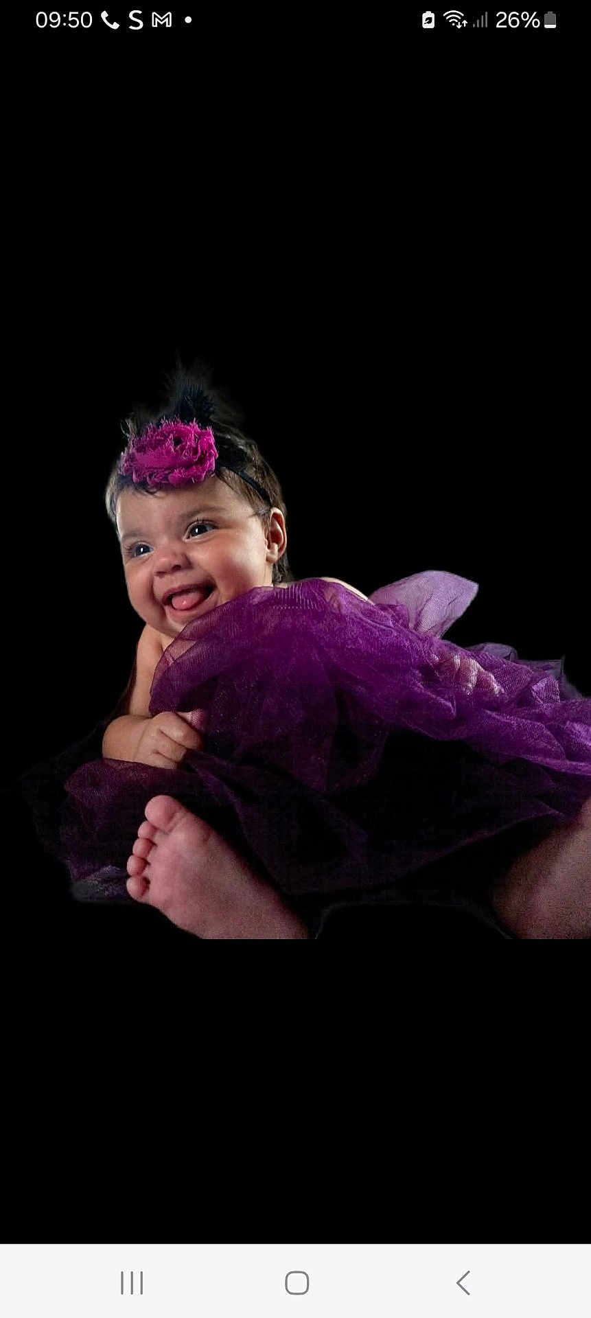 Nouva is registered to the contest to win money with this photo: baby, smiling, purple_tutu, headband, flower, portrait, infant, cute, happy, child, foot, black_background, clothing, tulle, cheerful, face, person, studio, cute_expression, closeup