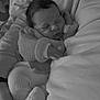 baby, newborn, sleeping, knit_sweater, sock, hand, arm, adult, lap, bedding, pillow, portrait, black_and_white, tiny_fingers, cozy, peaceful, infant_clothing, hair, closeup, resting
