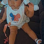 baby, child, hat, bib, butterfly, american_flag, pacifier, pacifier_clip, sitting, couch, footwear, sandals, waving, indoors, person, cute, clothing, accessory, face, expression