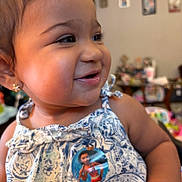 Zariyah is registered to the contest to win money with this photo: toddler, child, smile, face, earrings, dress, blue, white, floral_pattern, indoors, home, blurred_background, toy, sticker, cute, happy, portrait, person, skin, young_child
