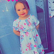 Sydney a rejoint le concours — aidez-le/la à gagner de superbes lots ! toddler, child, dress, barefoot, smiling, heart_emoji, glass_door, floor, tile, curtain, indoor, cartoon_print, pink_hearts, happy, standing, cute, girl, portrait, colorful, casual