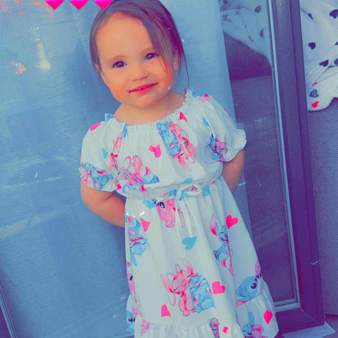 Sydney a rejoint le concours — aidez-le/la à gagner de superbes lots ! barefoot, cartoon_print, casual, child, colorful, curtain, cute, dress, floor, girl, glass_door, happy, heart_emoji, indoor, pink_hearts, portrait, smiling, standing, tile, toddler