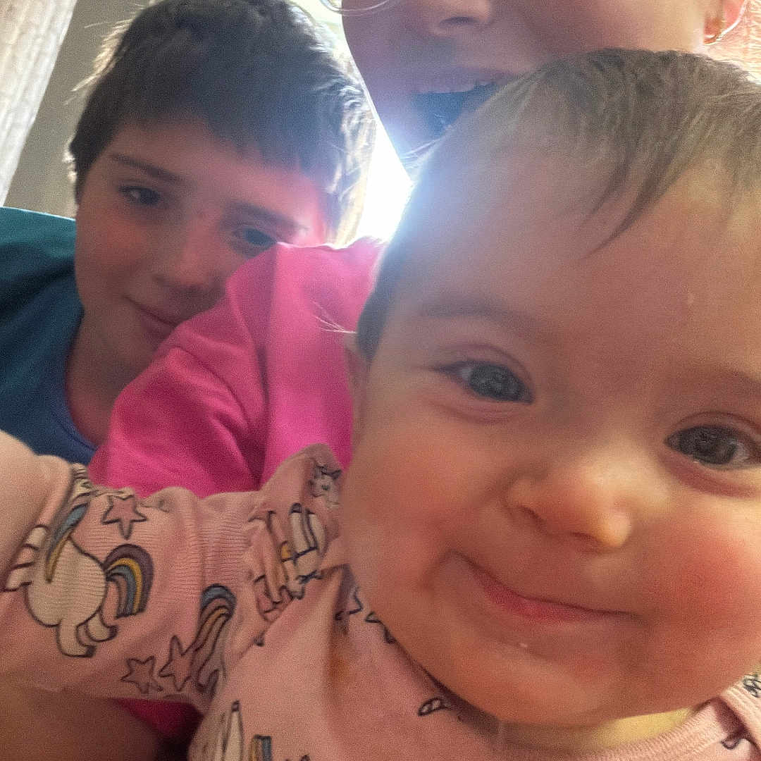 Nadine is registered to the contest to win money with this photo: baby, cheeks, child, close_up, clothing, curtain, eyes, face, glasses, happy, indoor, older_child, pajamas, playful, portrait, selfie, siblings, smile, toddler, unicorn_pajamas