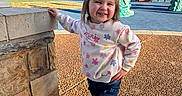 Shaylen is registered to the contest to win money with this photo: child, girl, playground, outdoor, smiling, casual_clothing, jeans, sneakers, bunny_ears, spring, sunlight, shadow, concrete, stone_wall, trees, play_equipment, happy, cute, posing, daytime
