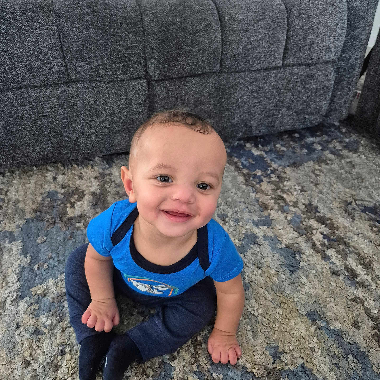 Caius joined the competition — help win amazing prizes! baby, child, smiling, blue_shirt, carpet, couch, indoor, sitting, happy, person, young_child, cute, face, portrait, floor, home, clothing, infant, hands, feet