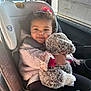 toddler, child, car_seat, stuffed_animal, toy, curly_hair, red_bow, hugging, cozy, sunlight, car_interior, seatbelt, happy, smile, clothing, pink_jacket, black_pants, window, child_safety, portrait