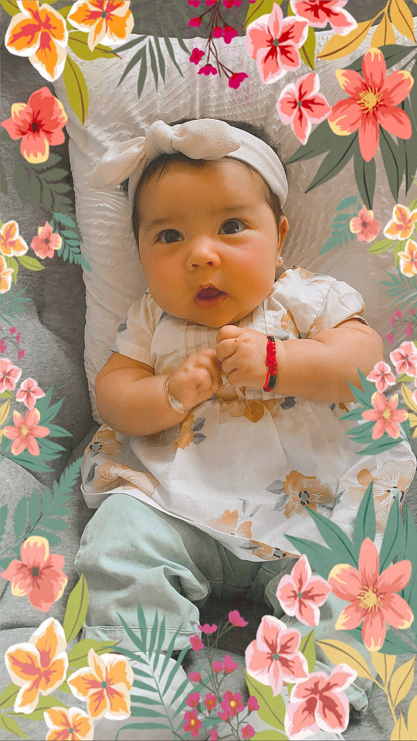 Antonella is registered to the contest to win money with this photo: baby, baby_toddler_clothing, cheek, child, eye, face, flower, happy, headwear, leaf, orange, pattern, people_in_nature, person, petal, pink, plant, product, skin, surprise