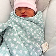 Eliana is registered to the contest to win money with this photo: newborn, baby, blanket, hat, sleeping, infant, cushion, baby_seat, soft_texture, patterned_fabric, wrapped, cozy, peaceful, indoors, headrest, resting, cute, small, child, portrait