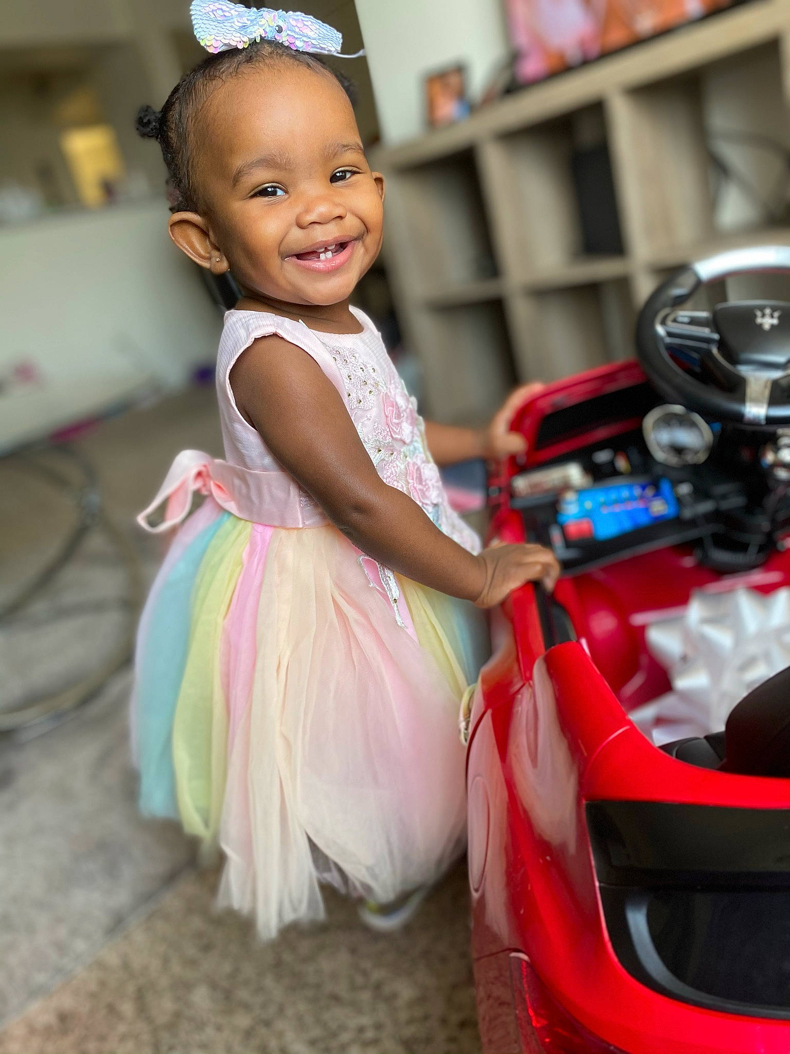 Amora is registered to the contest to win money with this photo: car, child, child_model, clothing, costume, dress, formal_wear, fun, hair_accessory, hairstyle, happy, joy, person, pink, smile, toddler, vehicle