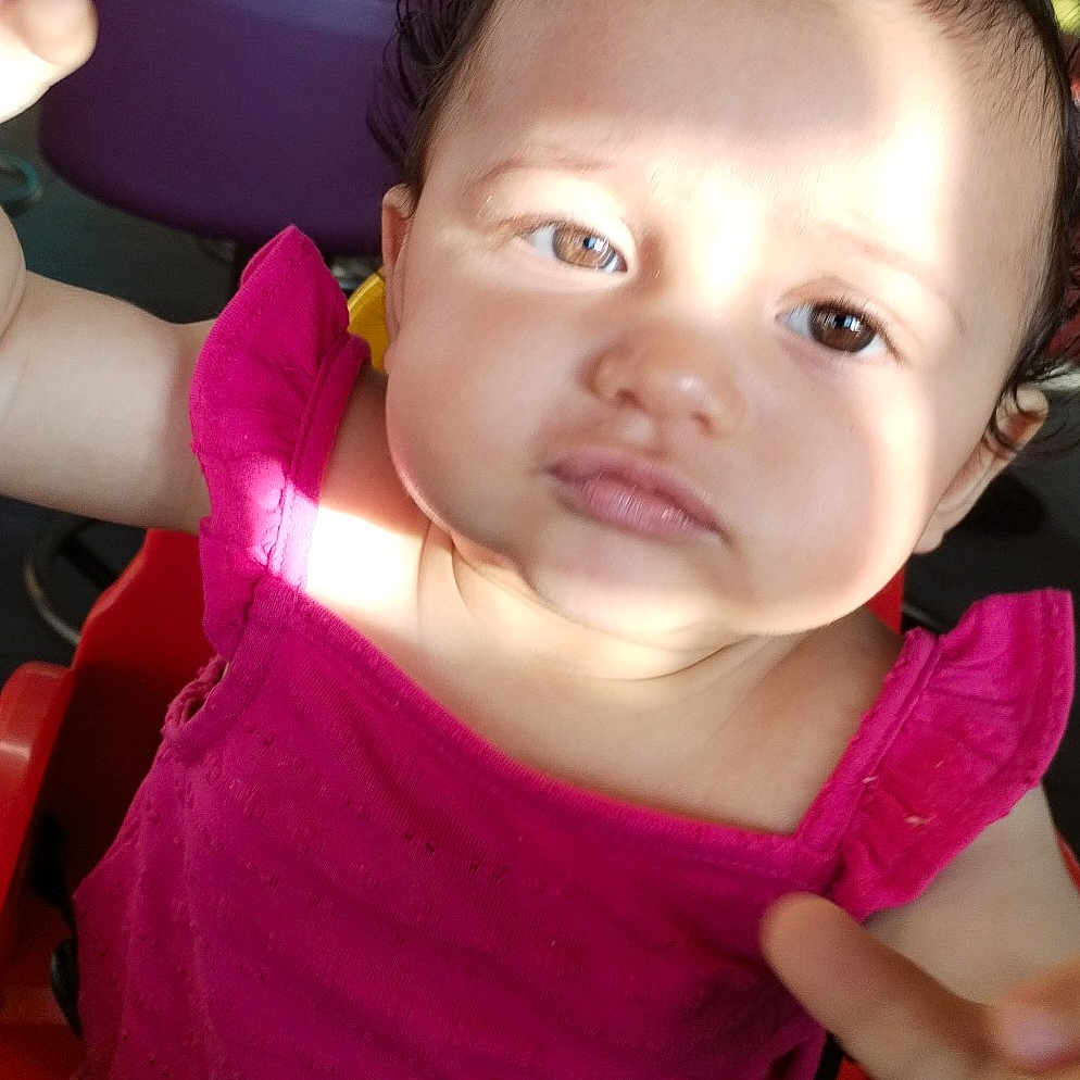 Widiane a rejoint le concours — aidez-le/la à gagner de superbes lots ! baby, child, closeup, curious, cute, expression, face, hair_clip, high_chair, indoor, infant, person, pink_clothing, portrait, reaching_hand, seat, shadow, skin, sunlight, young_child