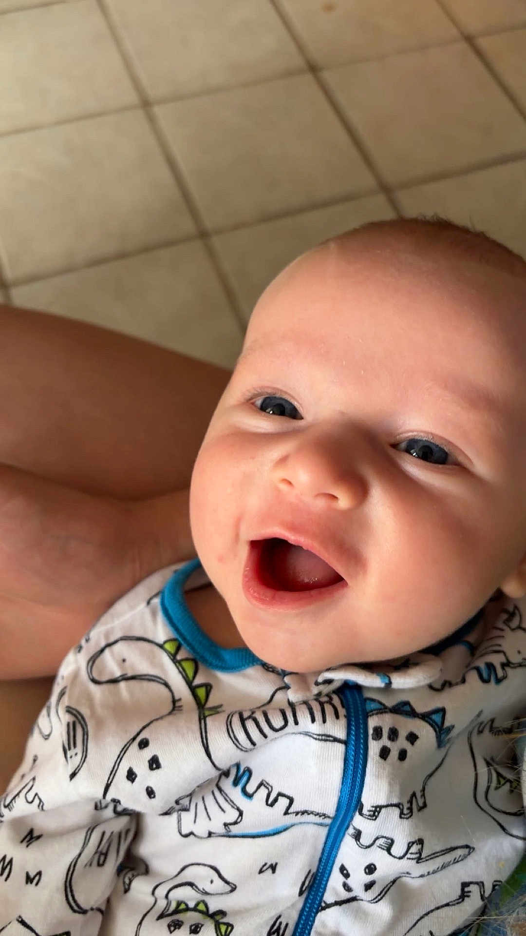 Aiden joined the competition — help win amazing prizes! baby, smiling, closeup, face, onesie, dinosaur_print, blue_trim, infant, happy, child, cute, portrait, human, skin, eyes, mouth, clothing, indoors, floor, tile