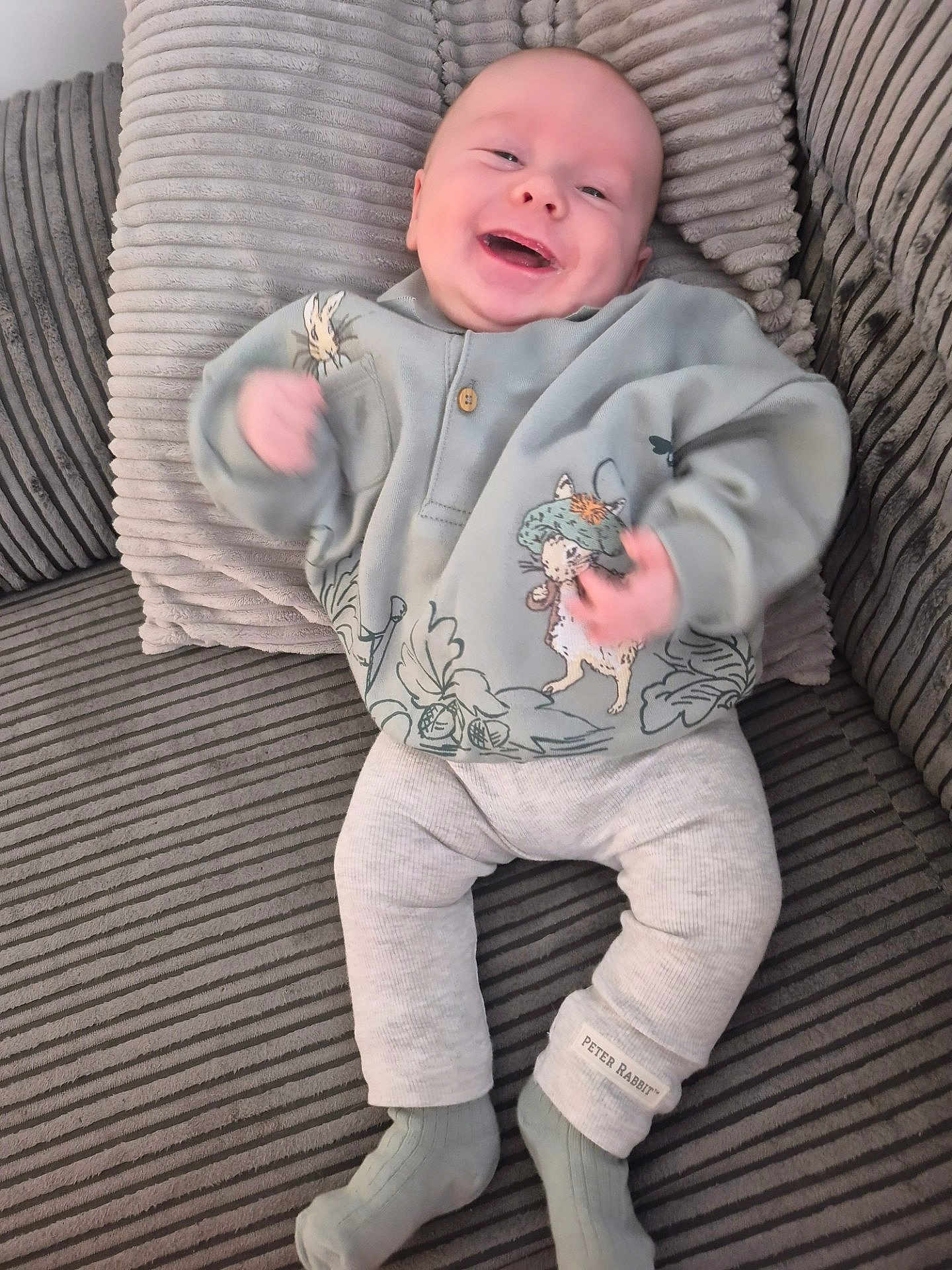 Cruz is registered to the contest to win money with this photo: baby, infant, smiling, happy, couch, striped, clothing, peter_rabbit, socks, sitting, cute, child, portrait, indoor, cozy, soft_fabric, playful, young, person, apparel