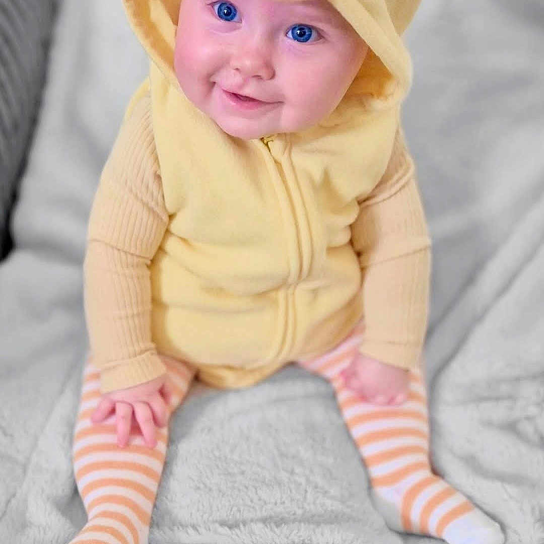 Savannah is registered to the contest to win money with this photo: baby, bonnet, cap, clothing, costume, face, happy, hat, head, hood, hosiery, knitwear, newborn, person, photography, portrait, sitting, smile, sock, sweater