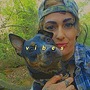 Teeny Tiny is registered to the contest to win money with this photo: bracelet, canine, cap, closeup, dog, face_piercing, greenery, hand, happy, nature, necklace, outdoor, person, pet, plaid_shirt, portrait, smile, tattoo, trees, vibes_text