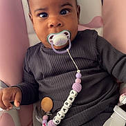 Diarry participe au concours pour gagner de l'argent avec cette photo : baby, child, pacifier, beaded_clip, curly_hair, baby_seat, pink, white, dark_clothing, ribbed_fabric, cute, infant, sitting, secure, curious, face, hand, indoor, comfort, young_child