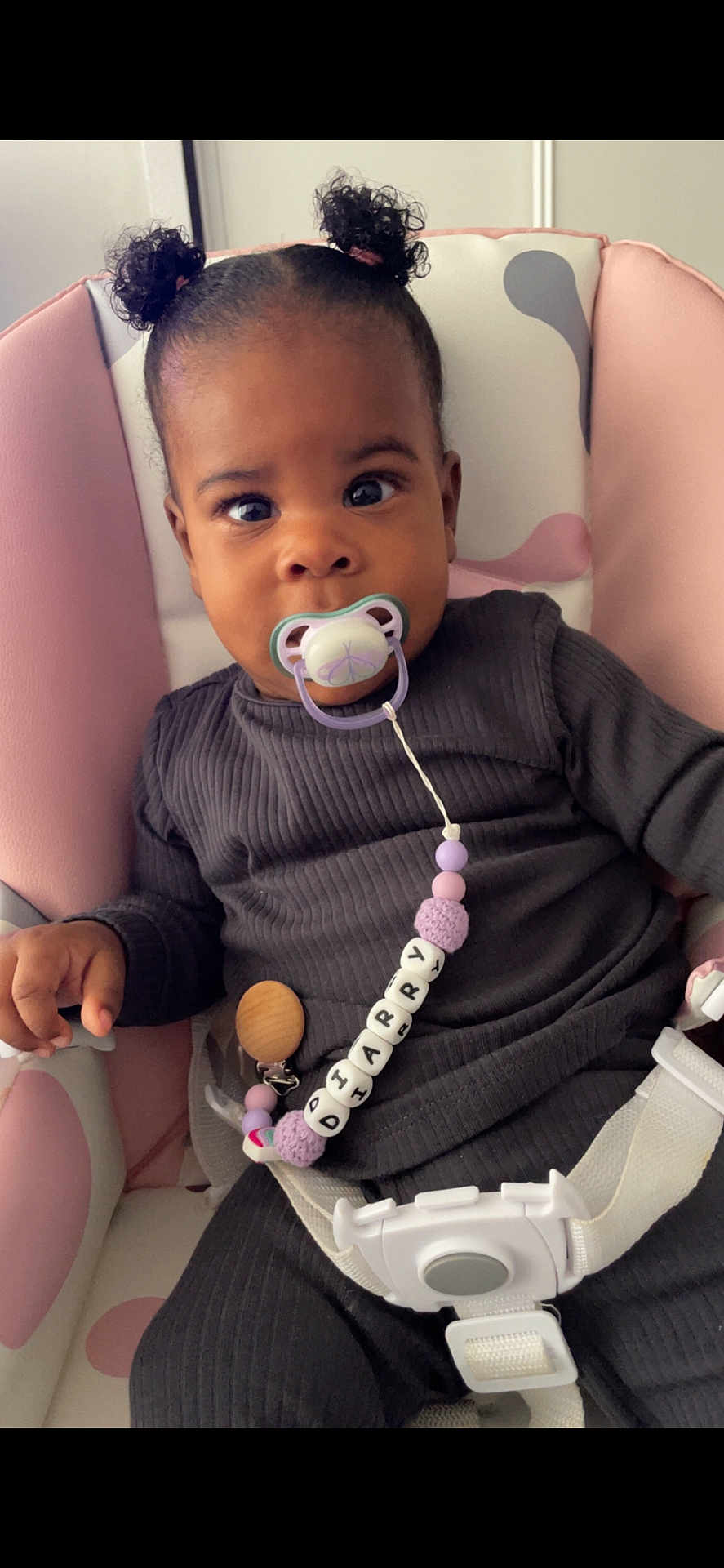 Diarry participe au concours pour gagner de l'argent avec cette photo : baby, child, pacifier, beaded_clip, curly_hair, baby_seat, pink, white, dark_clothing, ribbed_fabric, cute, infant, sitting, secure, curious, face, hand, indoor, comfort, young_child