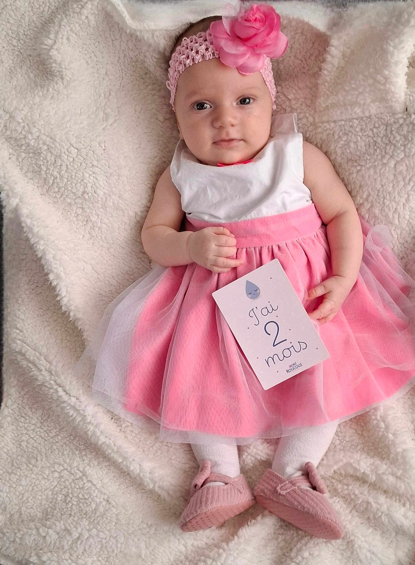 Méline participe au concours pour gagner de l'argent avec cette photo : baby, infant, pink_dress, headband, flower, blanket, white_tights, pink_shoes, card, milestone, portrait, cute, lying_down, soft_texture, celebration, child, young_baby, close_up, indoor, adorable