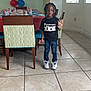 Davion is registered to the contest to win money with this photo: child, birthday_party, balloons, party_table, jeans, sneakers, black_tshirt, indoor, tile_floor, chair, window, decorations, hand_gesture, celebration, person, young_child, event, casual_clothing, smiling, standing