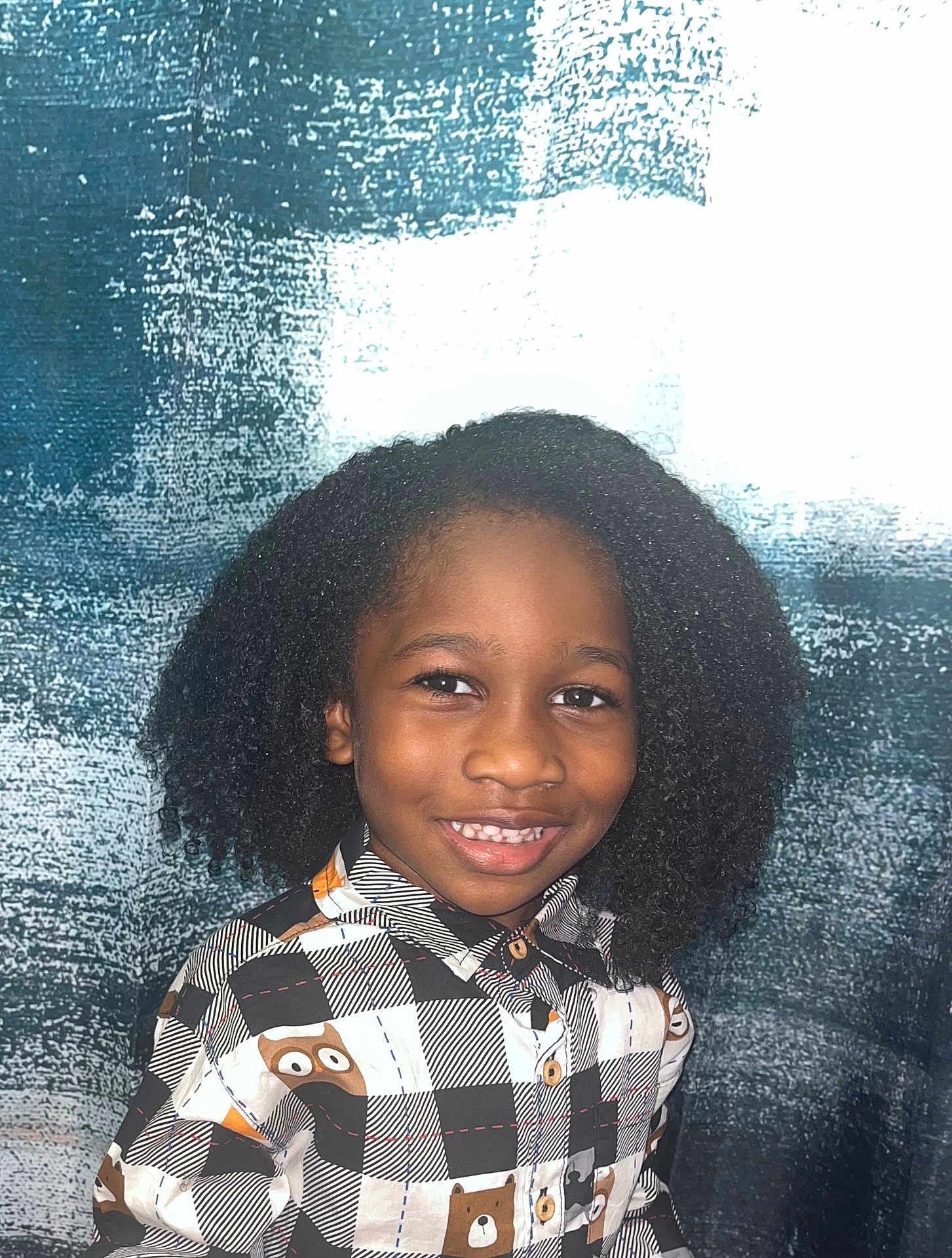 Davion is registered to the contest to win money with this photo: child, smiling, curly_hair, shirt, bear_pattern, portrait, happy, face, person, cute, indoors, fashion, childrens_clothing, buttoned_shirt, black_hair, young, casual_wear, eye_contact, standing, background