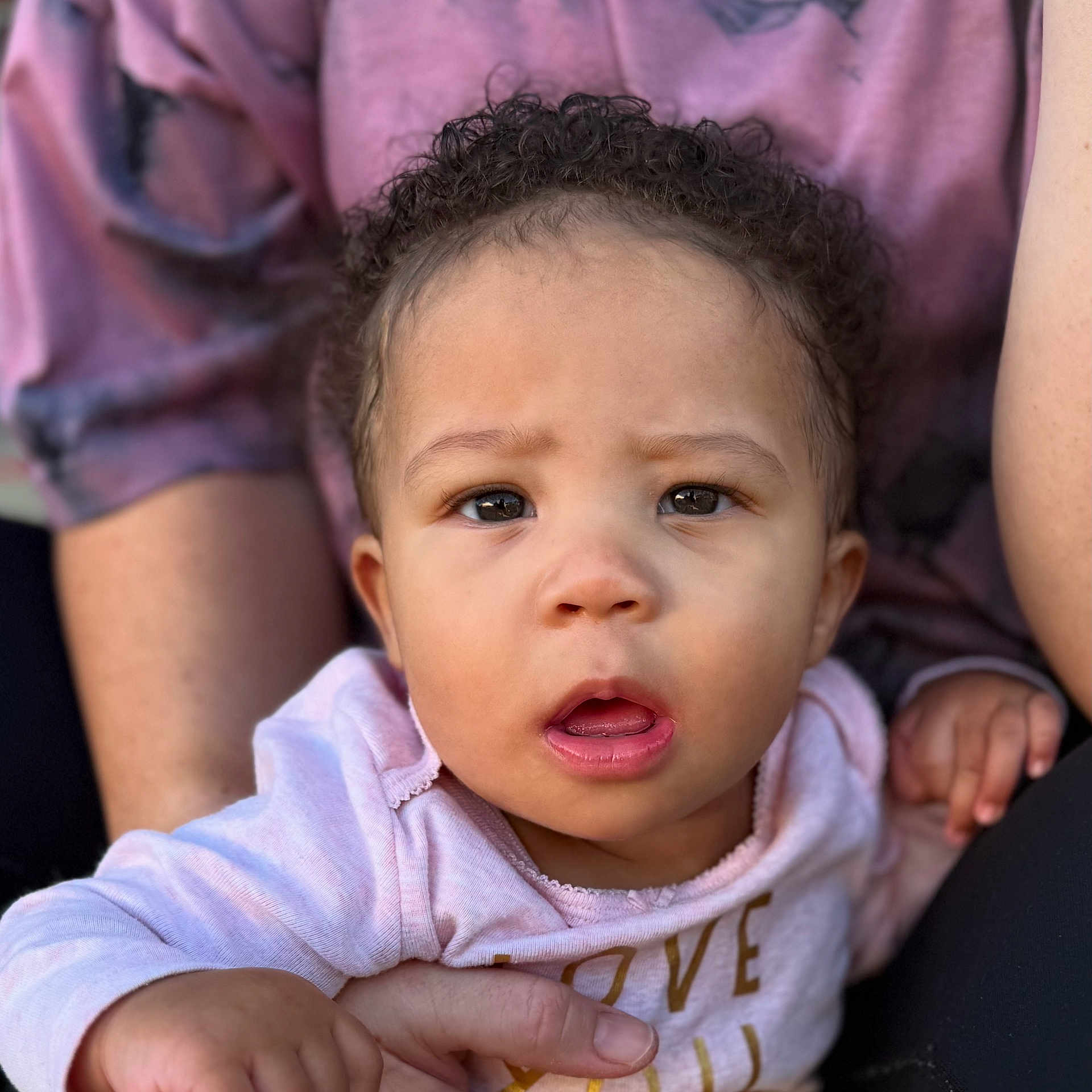 Heaveniyah is registered to the contest to win money with this photo: baby, candid, casual_wear, child, closeup, curly_hair, expression, eyes, face, hand, holding, human, indoor, mouth, person, pink_clothing, portrait, skin, soft_light, toddler