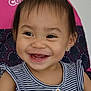 toddler, smiling, child, happy, portrait, striped_clothing, buttoned_top, hair_tie, earring, indoor, seat, patterned_fabric, pink_background, navy_blue, face, cute, young_child, person, laughing, closeup