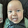 baby, tongue, car_seat, harness, green_shirt, close_up, face, infant, playful, child, seat, safety_label, smile, eyes, skin, head, expression, indoors, person, cute